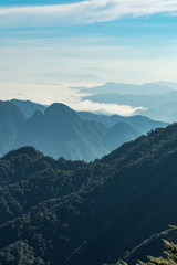 view of the far away mountain range covered in thick white cloud under hush sun light in the hazy morning