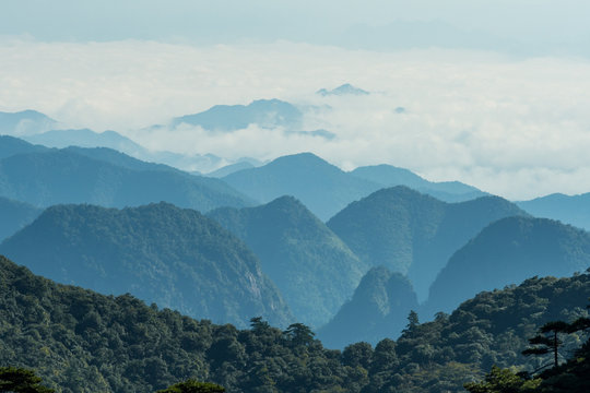 view of the far away mountain range covered in thick white cloud under hush sun light in the hazy morning