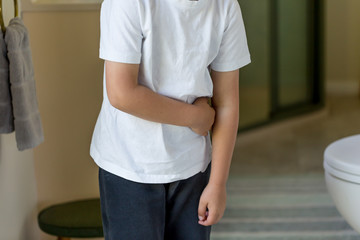 young boy holding his stomach near a bathroom