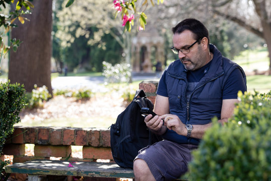 50 Year Old Man Checking His Mobile Phone In A Park