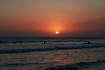 A beautiful sunset on a sea with surfers