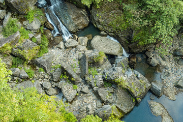 water in the stream rushing down the rocky creek covered in green view from above