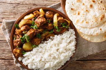 Traditional recipe for Indian chicken do pyaza (dopiaza) with onion and spice and garnish of rice close-up on a plate with flatbread. horizontal top view © FomaA