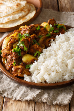 Traditional recipe for Indian chicken do pyaza (dopiaza) with onion and spice and garnish of rice close-up on a plate with flatbread. vertical