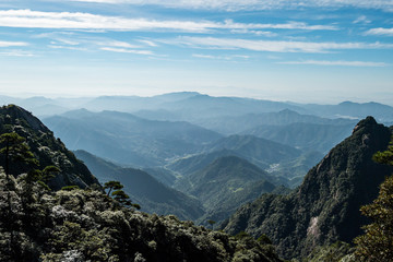 forest covered valley floor covered in haze cause by the rising sun above the cloud