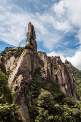 unique rock formation covered with forest on the peaks of Mount Sanqing under the cloudy blue sky