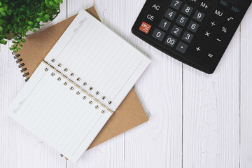 Fountain pen or ink pen with notebook paper and calculator on wooden working table with copy space, office desk concept. top view.