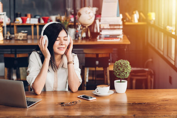 Lifestyle freelance woman he using earphones listening music during working on laptop computer