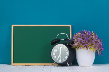 Blank green chalkborad with wood frame and little decorative tree in white vase and vintage alarm...