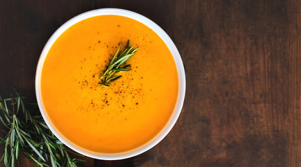 Pumpkin and carrot  Cream soup on  wooden background. Autumn cream-soup in country style. Top view. Copy space.