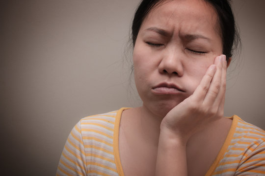 Asian woman suffering from toothache and have to see dentist. Concept of teeth problem.