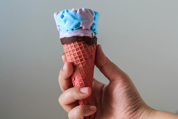 Woman hand holding an colorful ice cream cone.