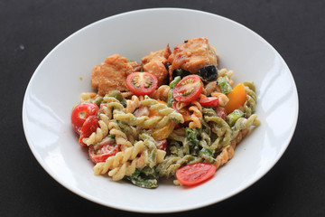 Whole wheat pasta with cream sauce on black background.