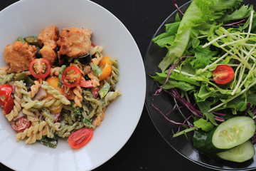 Whole wheat pasta with fresh vegetable salad on black background.Clean eating, dieting, vegan food concept.