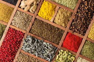 Spices and herbs in wooden boxes. Multicolored condiments close-up, as background.