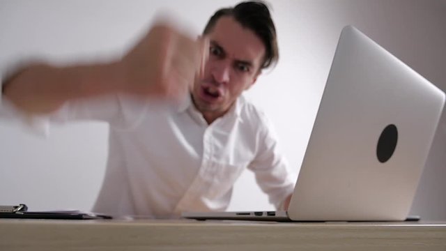 Angry businessman beats his fist on the table. Stress at office work. The boss shows aggression.