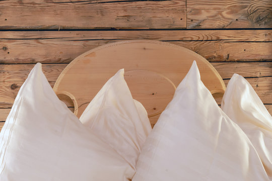 Kopfkissen auf einem Holzdoppelbett vor einer Holzwand