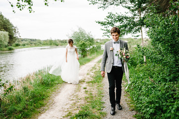 Portrait of an attractive groom escapes or run from bride on nature in the park. Romantic couple of...
