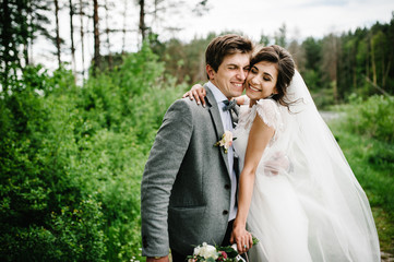 Attractive couple newlyweds on track in the garden. Outdoors. Romantic wedding moment.
