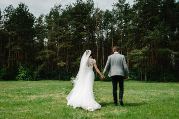 Attractive couple newlyweds is walking back on a trail in an green forest. Happy and joyful moment.