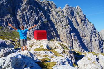 Emergency hut called Bivacco Gorizia with young man and high mountains in the background in...