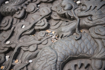 Old dragon sculpture with many coins to prepare for the merit at jing'an temple in shanghai, china.