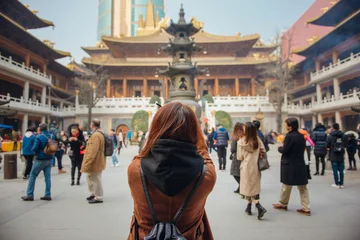 Cercles muraux Shanghai Vue arrière d& 39 une jeune femme voyageant prenant une photo au temple jing& 39 an en chine. Une jeune femme asiatique en veste à l& 39 aide d& 39 un appareil photo prend une photo du temple de shanghai.