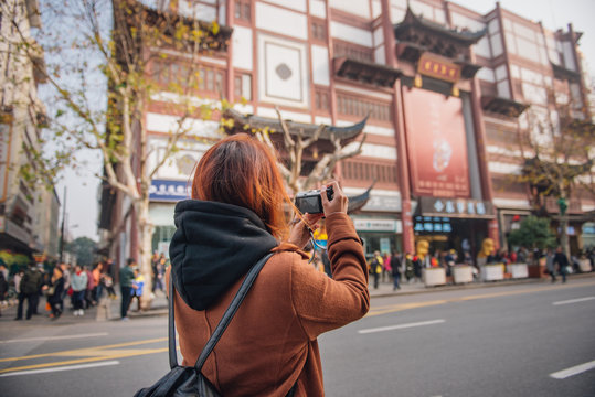Young woman traveler taking photo picture at yu yuan garden. Young asian woman in jacket clothes using camera take a picture of traditional characteristic commercial street in shanghai, china.