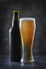 Bottle of cold beer and glass with foam