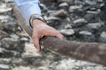 male hand hold on to the old wooden handrail
