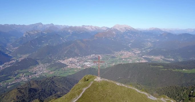 4K Drone aerial view to the Seriana valley and Orobie Alps in a clear and blue day. The cross at the top of the mountain. Landscape from Pizzo Formico Mountain, Bergamo, Italy