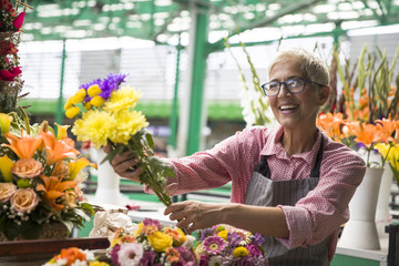Senior woman sales flowers on local flower market