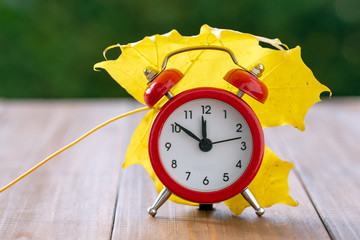 Red vintage clock and mable leaf. Autumn time change