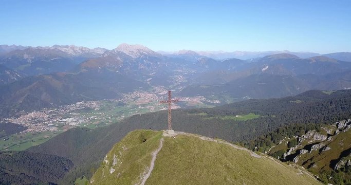 4K Drone aerial view to the Seriana valley and Orobie Alps in a clear and blue day. The cross at the top of the mountain. Landscape from Pizzo Formico Mountain, Bergamo, Italy
