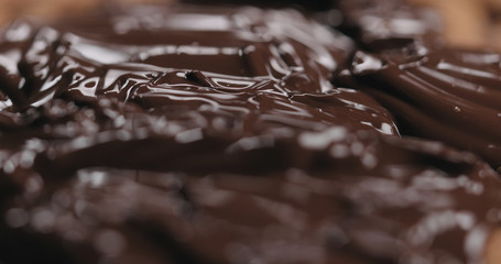 closeup covering roasted almonds with melted dark chocolate