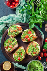 Bruschetta with fresh pesto, mozzarella and cherry tomatoes on cutting board