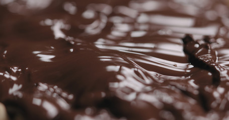 closeup covering roasted hazelnuts with melted dark chocolate