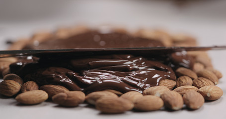 closeup spreading chocolate over roasted almonds