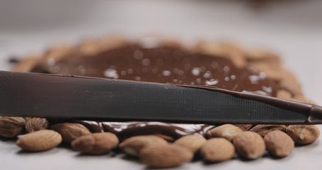 closeup spreading chocolate over roasted almonds