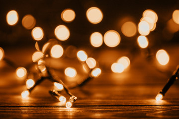 Festoon golden lights on a wood table, bokeh background.