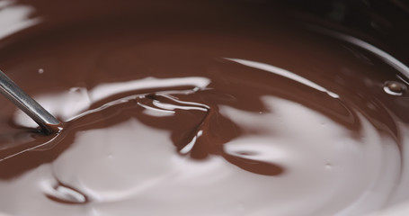 closeup stirring melted dark chocolate with spoon