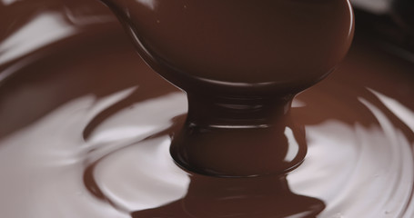 closeup pouring melted dark chocolate from spoon