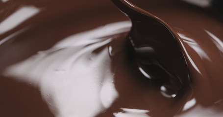 closeup stirring molten dark chocolate with spoon