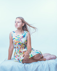 Girl sitting on a white background and looking into the distance