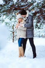 Fototapeta na wymiar winter portrait of happy couple having fun in snowy forest. Man and woman spending vacations outdoor on the walk
