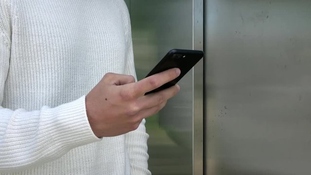4K. Businessman using his smartphone. Person typing on the phone, surfing the internet and checking social networks. He is near an elevator-Adrian