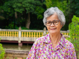 Portrait of senior asian woman stand wearing glasses and smiling in garden.