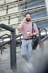 Fototapeta premium Smiling bearded man having a phone conversation outdoors