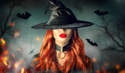 Halloween. Sexy witch portrait. Beautiful young woman in witches hat with long curly red hair