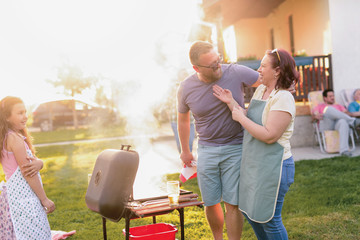 Picture of middle age couple making barbeque in their backyard. Family lunch on summer day.